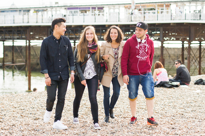 EC students walking on the beach in front of the Brighton Pier.