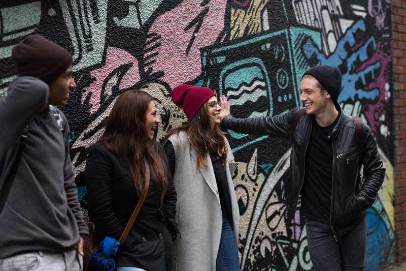 Students taking English courses in Bristol at EC, outside near a beautiful graffiti wall